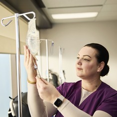 An INVIVA clinic nurse sitting beside a patient in an infusion chair, with the patient smiling at the nurse.